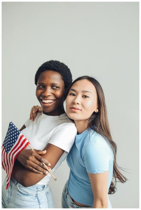 Two diverse women smiling and holding an American