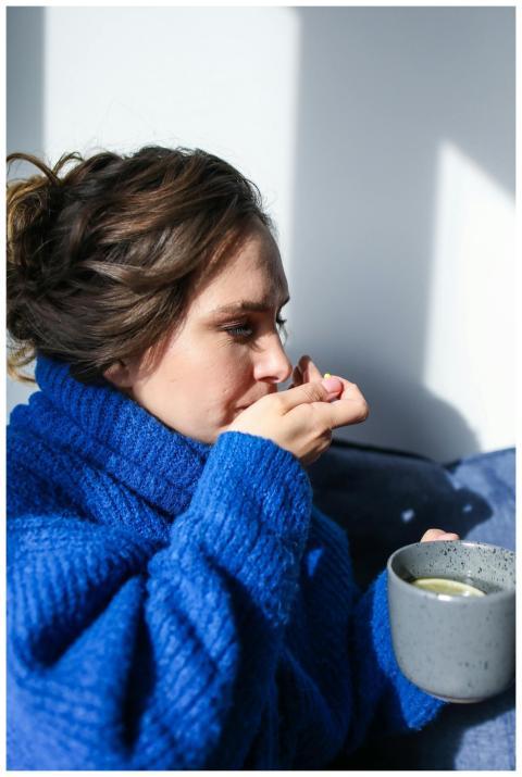 A woman in a blue sweater taking medication with a