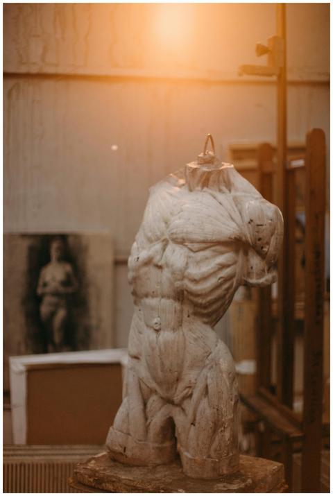A classic marble torso sculpture illuminated by wa