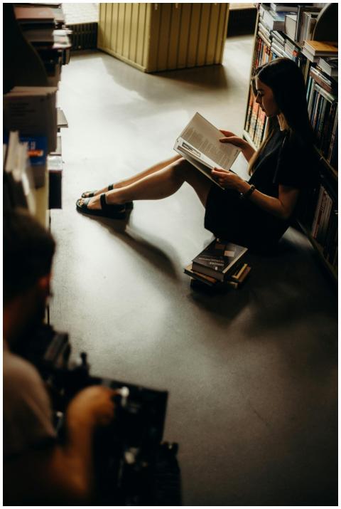 A young woman enjoys reading in a dimly lit bookst