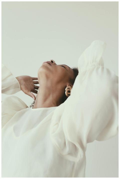 A stylish woman with curly hair strikes a graceful