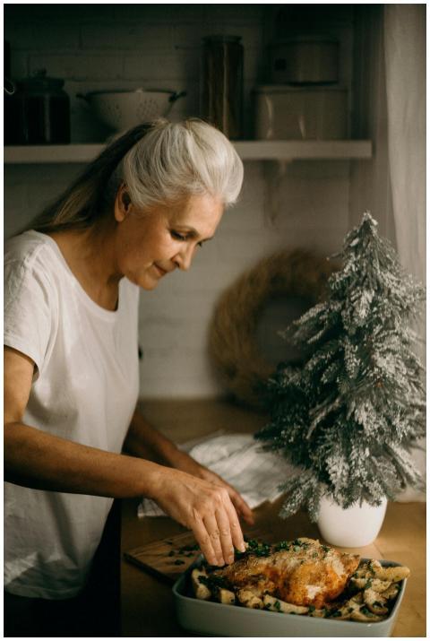 Senior woman garnishing a roast dish beside a smal