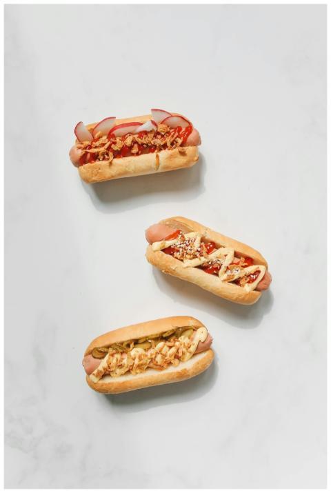 Three artisanal hot dogs with gourmet toppings on