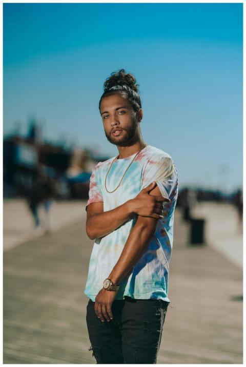 A fashionable adult male stands confidently on a s