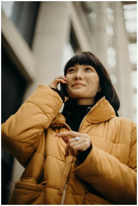 A young woman in a yellow jacket smiling while tal