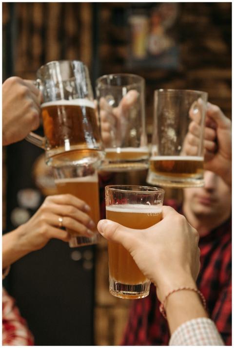 Group of friends clinking beer mugs, enjoying a fu