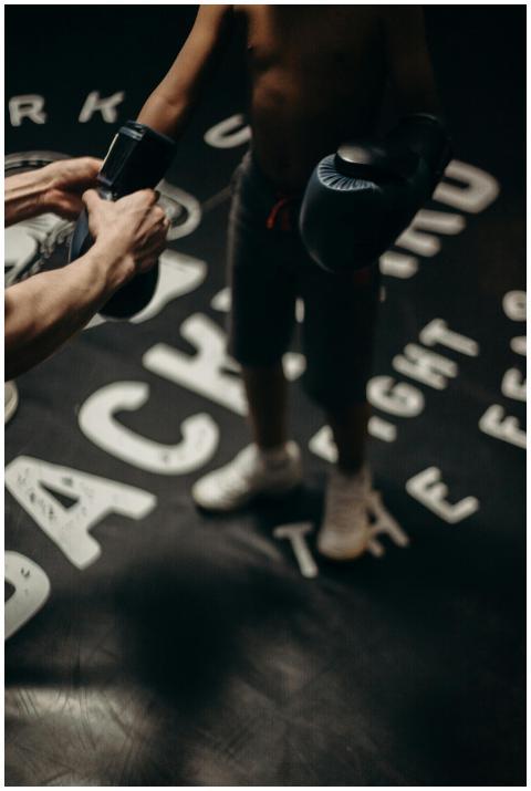 A child boxer receiving guidance from a trainer in