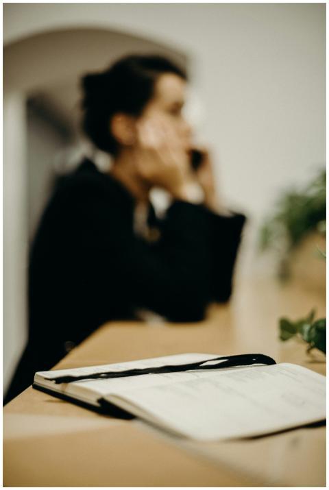 A woman in focus reflecting at her desk with an op