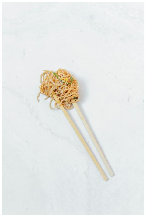 Close-up of noodles held by chopsticks on a marble