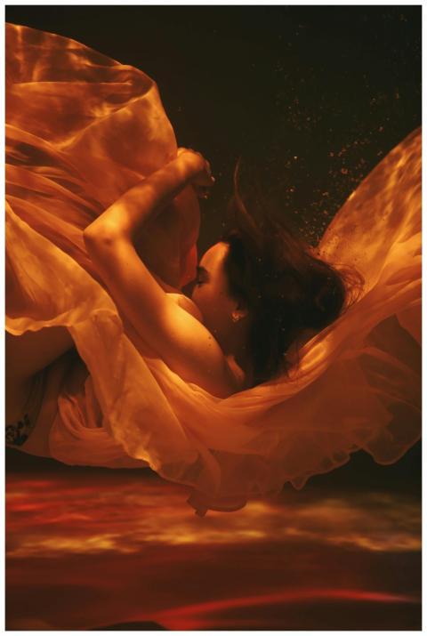 A woman floats gracefully underwater with flowing