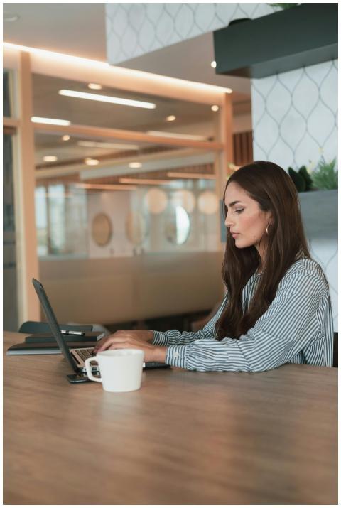 Focused young woman typing on a laptop in a stylis