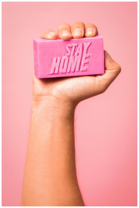 A pink bar of soap with 'Stay Home' text held in a