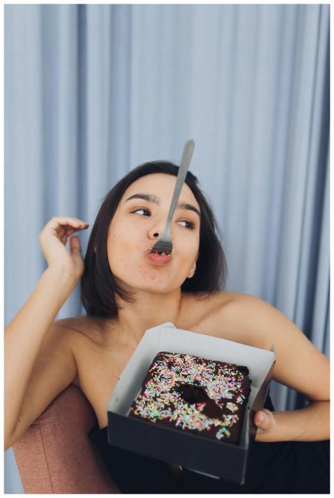 Woman with fork playfully eating chocolate cake wi