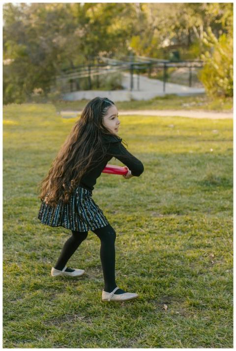 A young girl with long hair plays frisbee on a sun