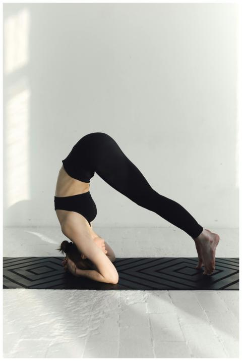 Woman practicing a headstand yoga pose indoors, em