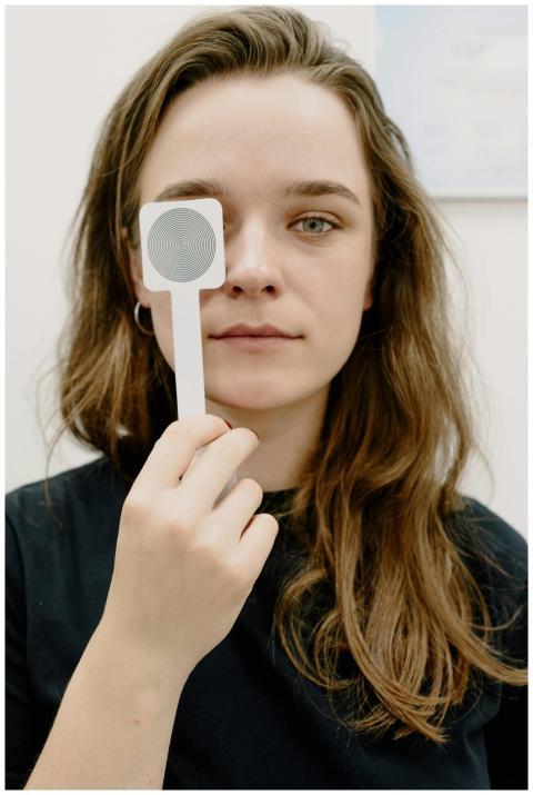 Young woman holding occluder during an eye exam in
