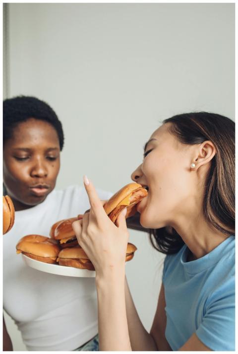 Happy women indulging in delicious burgers indoors