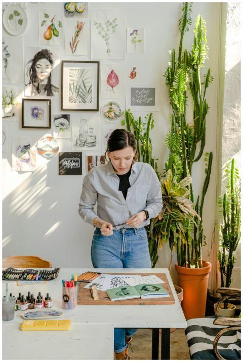A dedicated artist working in a bright, plant-fill