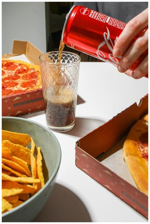 Close-up of pizza, nachos, and cola being poured,