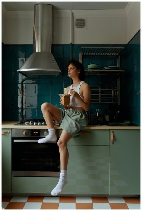 Woman in a tank top enjoying a meal on a kitchen c