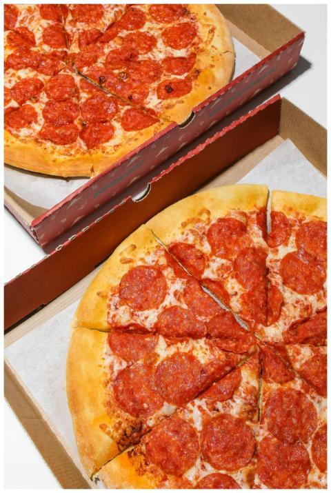Two pepperoni pizzas in open boxes ready to be ser
