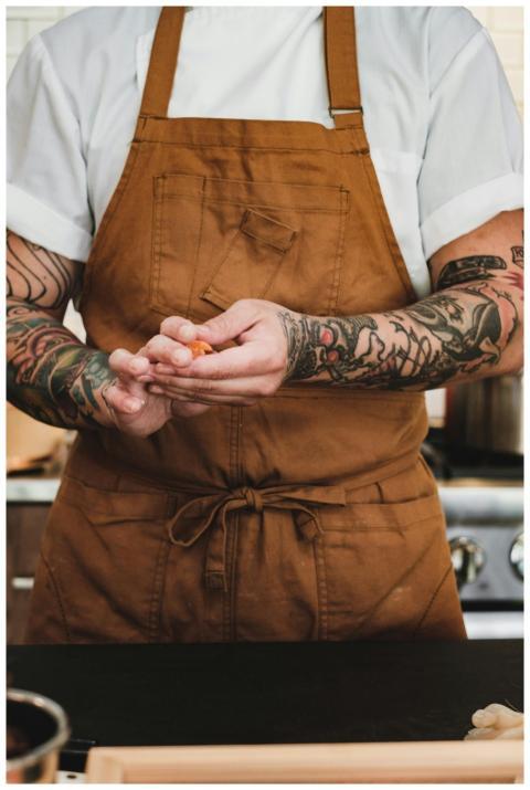 Close-up of tattooed chef preparing food in a mode