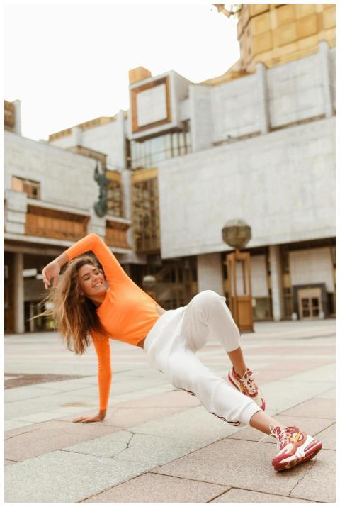 A confident woman performs breakdance moves outdoo