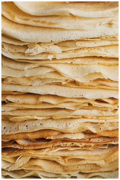 A close-up view of a stack of golden crêpes, showc