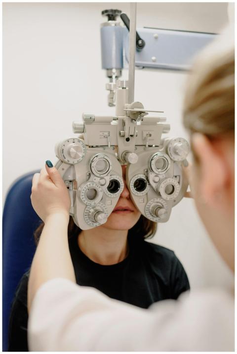 An optometrist conducts an eye exam with a phoropt