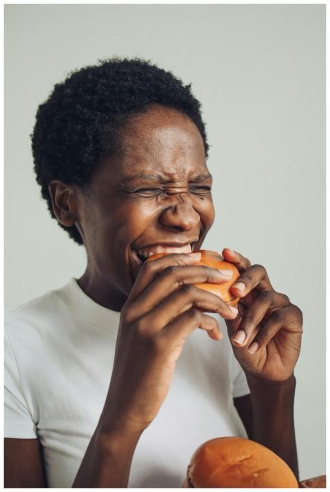 Smiling woman taking a bite of a savory burger, ex