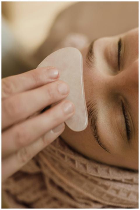 Close-up of a woman receiving a soothing gua sha f