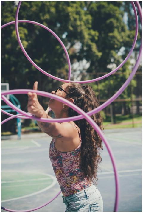 A young woman enjoying hula hoop tricks at a park