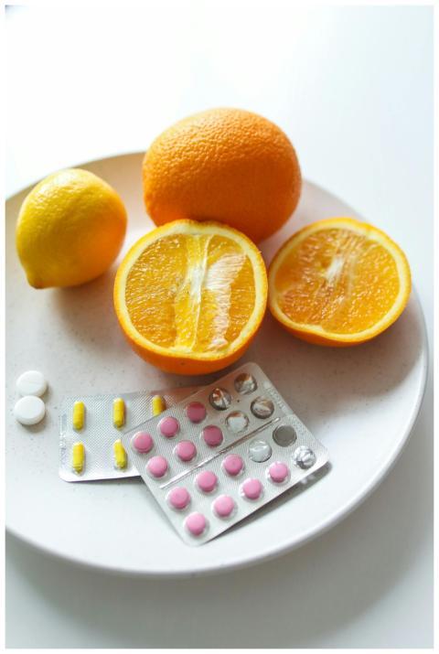 A close-up of oranges and pills on a white plate,