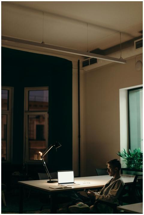 Man working late in an office using a laptop under