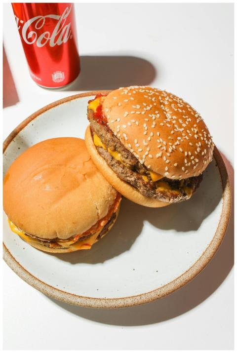 Two cheeseburgers with a Coca-Cola can on a plate,
