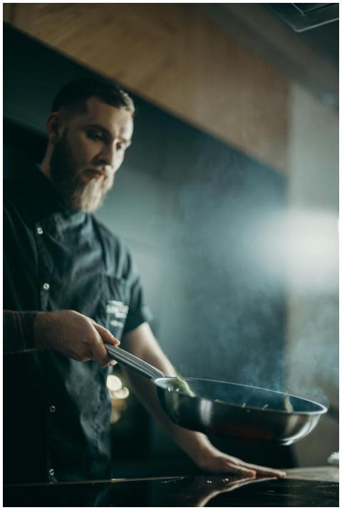 A focused chef prepares a meal using a frying pan