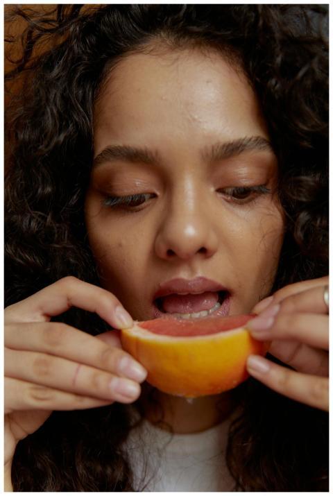 Close-up of a woman savoring a fresh grapefruit sl