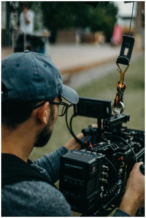A focused filmmaker operating a cinema camera outd