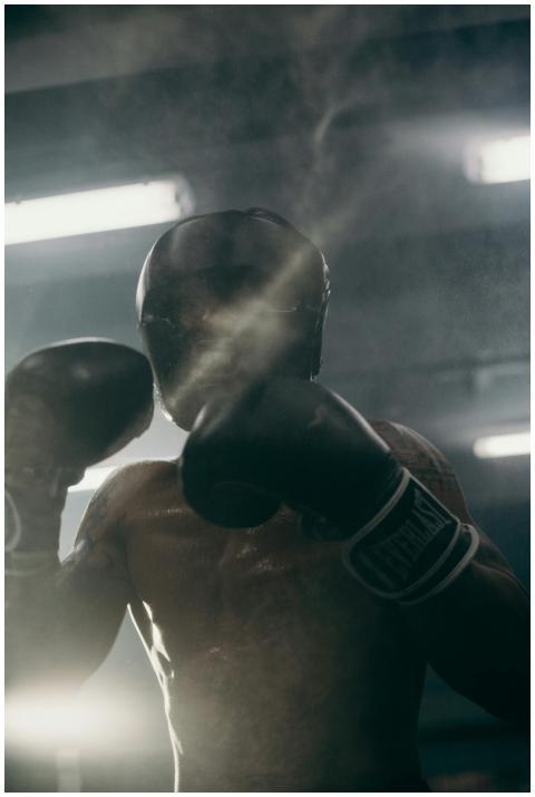 A focused boxer practices his punches in a shadowy