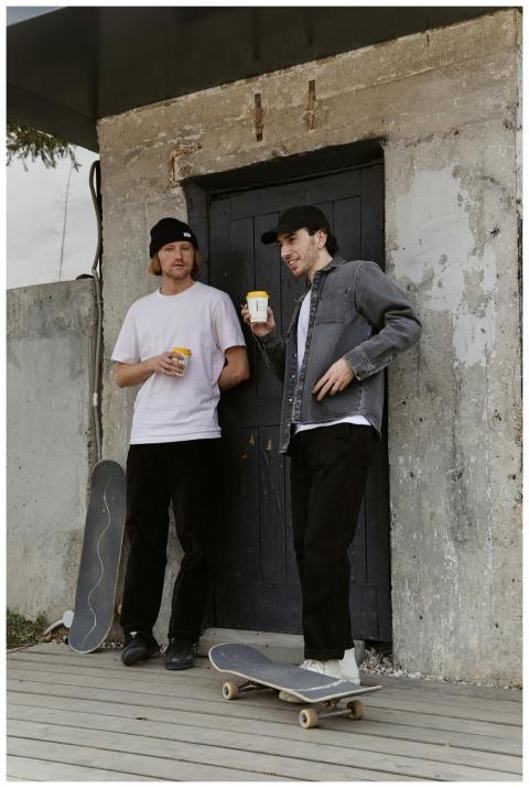 Two skateboarders enjoying a coffee break outdoors