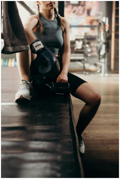 Young woman boxer resting on boxing ring edge in a