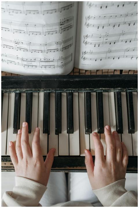 Child playing piano with sheet music above, focusi