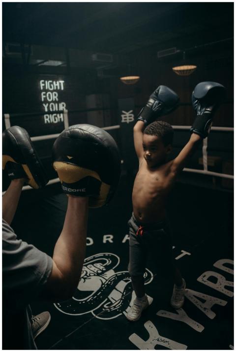 A child boxer raises gloves in victory during spar