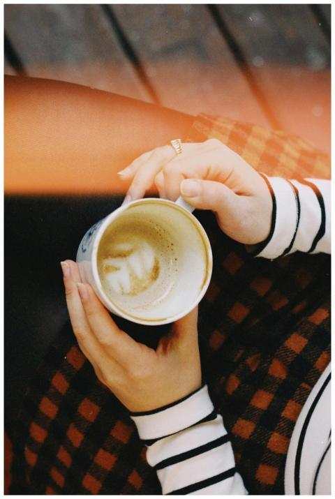 A close-up top view of a woman holding a coffee cu