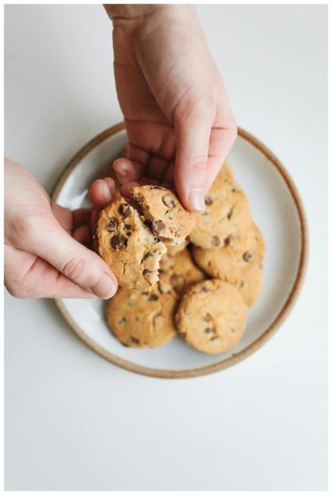 Close-up of hands breaking a chocolate chip cookie
