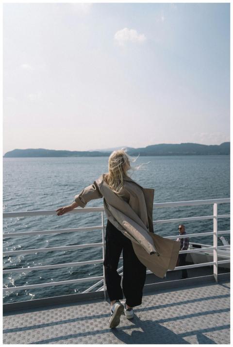 A woman stands on a ferry overlooking the ocean, e