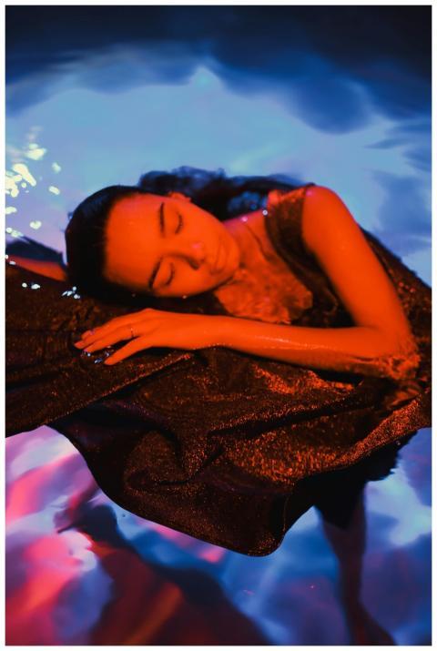 A woman peacefully floating in vibrant blue and or