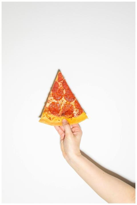 A hand holding a pepperoni pizza slice isolated on