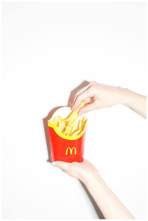 Close-up of hands holding McDonald's fries in whit