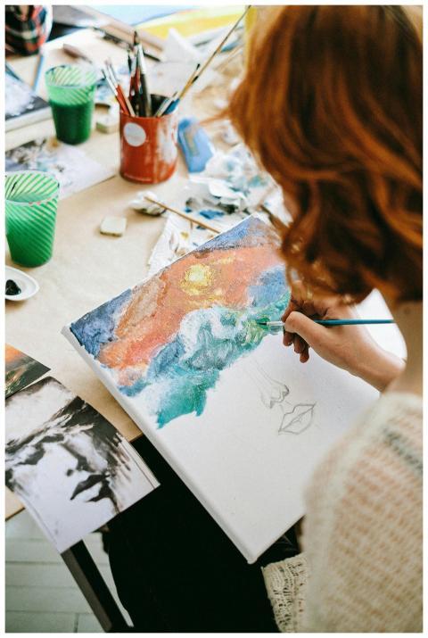A young woman artist painting a colorful canvas in